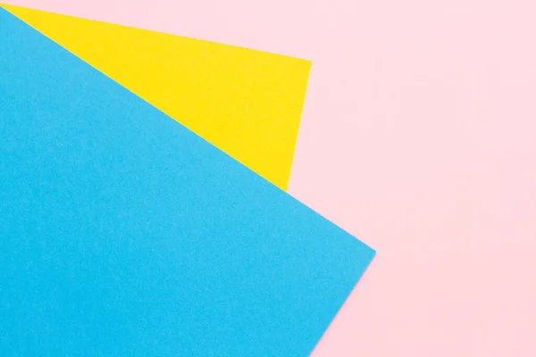Pedaços de papel amarelo e azul sobre um fundo rosa — Fotografia de Stock