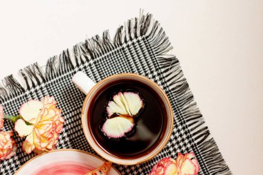 Gri bir peçetede çiçek yaprağı olan bir fincan kahve.