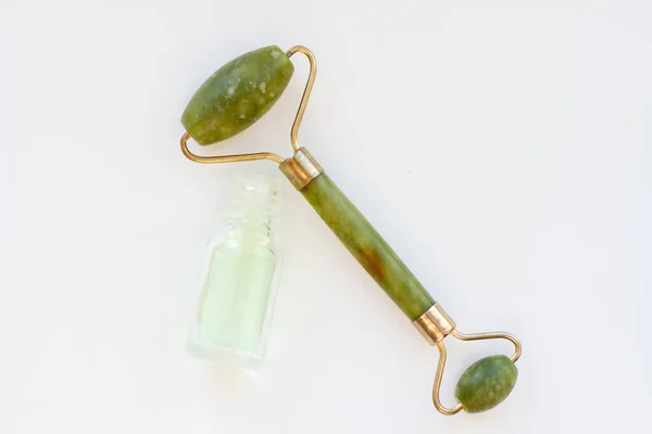 Groene jade stone massager en flessen parfum met groene vloeistof — Stockfoto