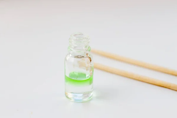 Aceite de aroma verde para aromaterapia en una botella de vidrio con palos de madera — Foto de Stock