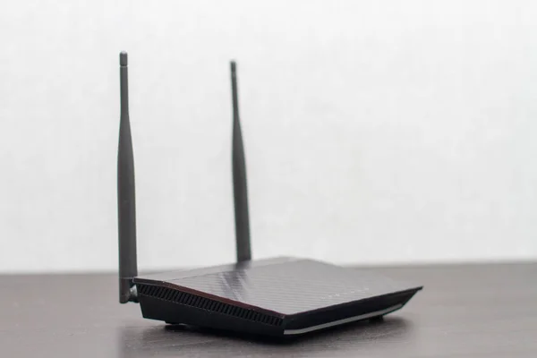 Черный беспроводной маршрутизатор с антеннами на черном столе компьютера на сером фоне — стоковое фото