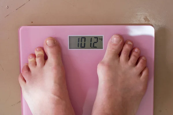 Pernas do homem em uma balança de chão com indicação de um grande peso — Fotografia de Stock