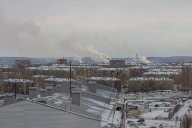 Bitkilerden oluşan boruları olan kirli bir sanayi şehrinin manzarası.