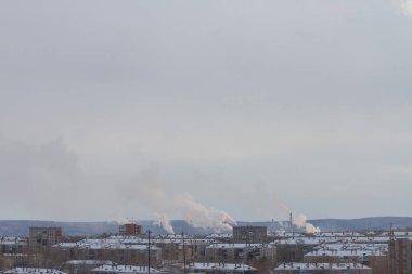 Bitkilerden oluşan boruları olan kirli bir sanayi şehrinin manzarası.