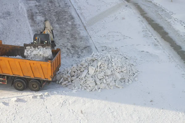 tractor loads the clean snow on the dump truck