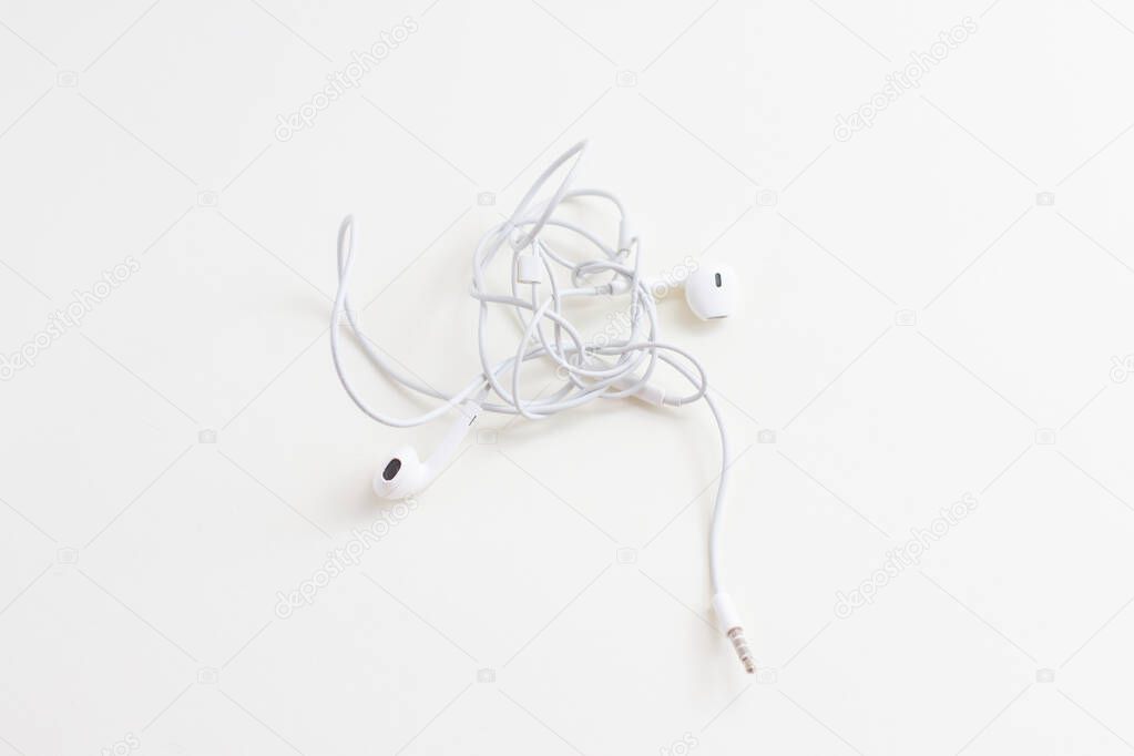 tangled wires of white headphones on a white background