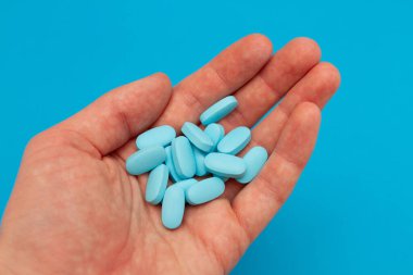 Mavi hapları tutan bir adamın eli