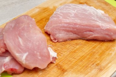 Kesme tahtasında dilimlenmiş taze domuz eti parçaları.
