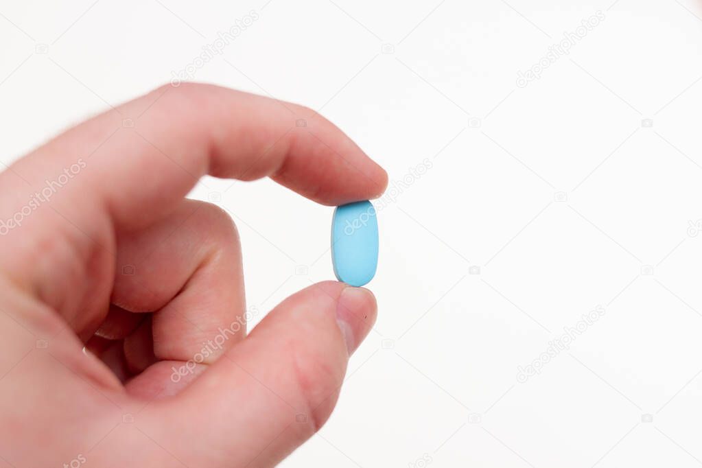 Man hand with blue capsule tablet
