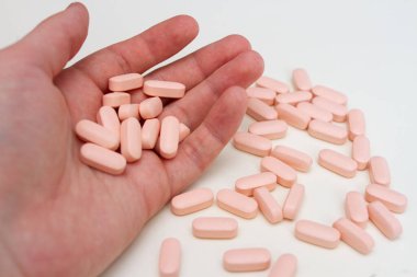 Bir avuç pembe hap. İnsan vitaminleri avucunun içinde tutar.