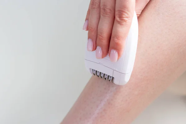 Kobieta depilacja nogi z białym depilatorem elektrycznym — Zdjęcie stockowe