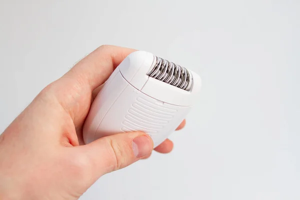 White epilator in a female hand on a white background. Hair removal device. — Stock Photo, Image