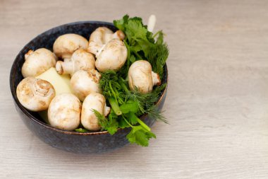 Taze şampiyonlar ve sebzeler mutfak masasındaki kasede..