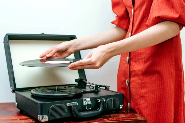 Mladá žena na retro šaty hraje vinylovou desku na gramofonu — Stock fotografie