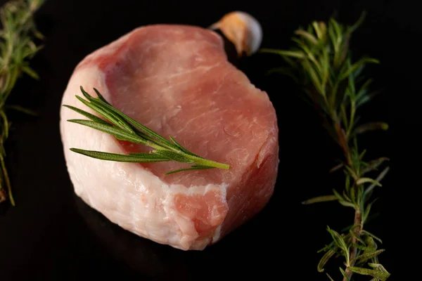 Rauw stuk voor steak van vlees met rozemarijn takken op een zwarte achtergrond — Stockfoto