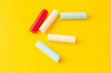 Parlak sarı arka planda hijyenik ruj sürmüş çok renkli tüpler..