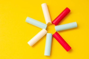 Güneş şeklinde sarı bir arka planda parlak renkli kozmetik ruj..