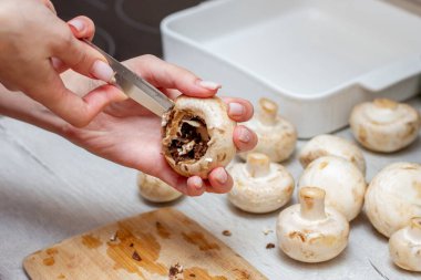 Kız mutfak masasında taze şampiyonlar pişiriyor. Mutfak bıçağı kızların elinde..