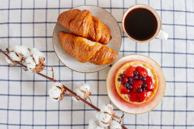 Masada bir fincan kahve ve çilekli kek ve kruvasan. Güzel kahvaltı..