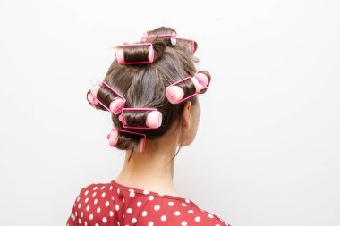 Esmer bir kızın kafasındaki kıvırcık saçlar için plastik bigudiler..