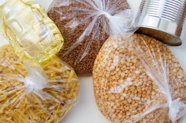 Beyaz arka planda kriz yemekleri. Plastik poşetlerde çeşitli mısır gevrekleri ve konserve ürünler. Temel Ürünler.