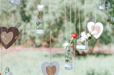 Açık hava düğün fotoğrafları için dekor. Doğada dekore edilmiş fotoğraf bölgesi. Mini vazolar ve çiçek buketleri.