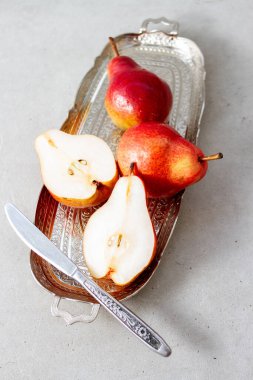Tepside bir bıçakla olgun bir armut. Yarısı, gri arka planda olgun.
