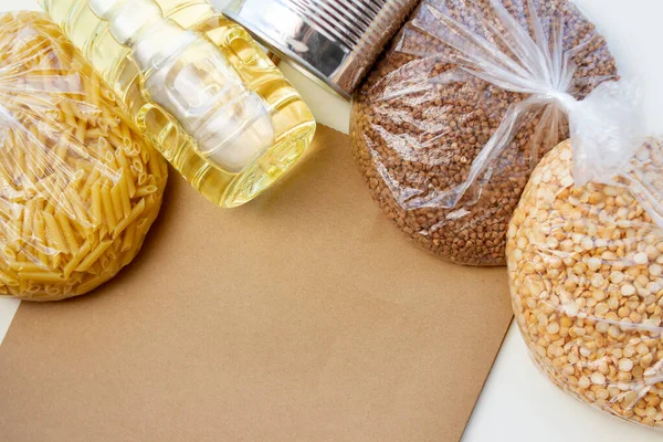 Donaciones de alimentos con diversos cereales. Bolsa de papel y aceite de girasol. Conjunto de alimentos para la crisis. Enfoque selectivo — Foto de Stock