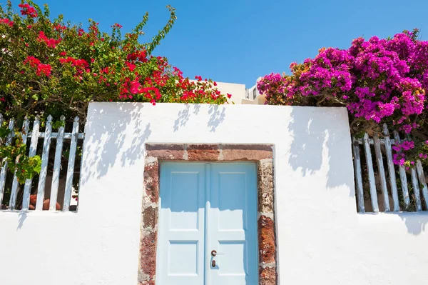 Fehér építészet, kék ajtó, és a rózsaszín virágok — Stock Fotó