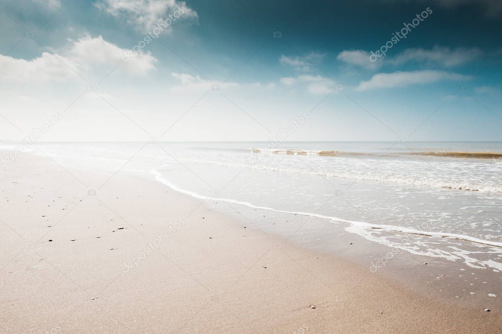 Sandy beach and blue sky with clouds.
