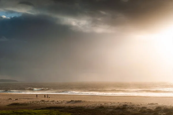 Mensen wandelen langs de kust van de Atlantische Oceaan bij zonsondergang — Stockfoto