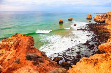 Portekiz, Algarve 'deki Atlantik Okyanusu kıyısındaki kayalar. Güzel yaz deniz manzarası, ünlü seyahat beldesi.