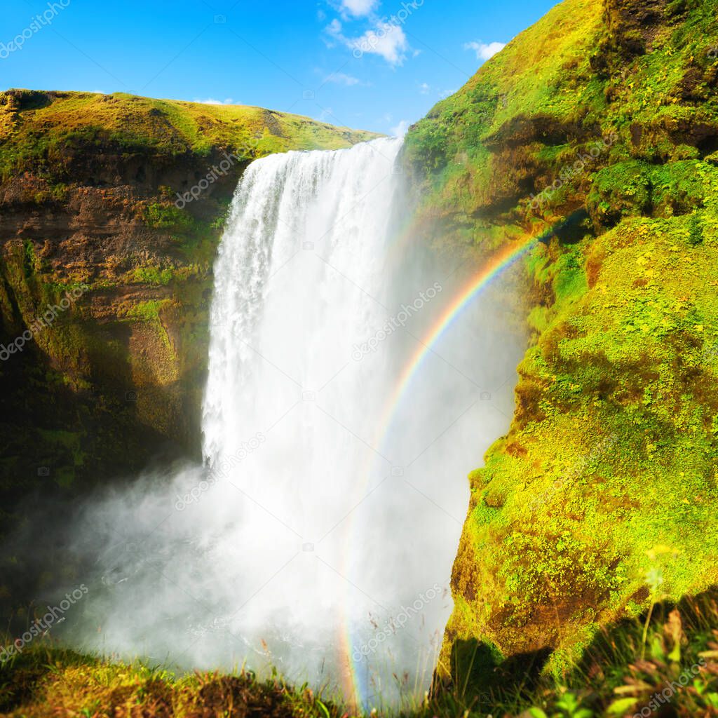 Skogafoss waterfall with rainbow and green cliffs, southern Iceland. Summer landscape. Famous travel destination