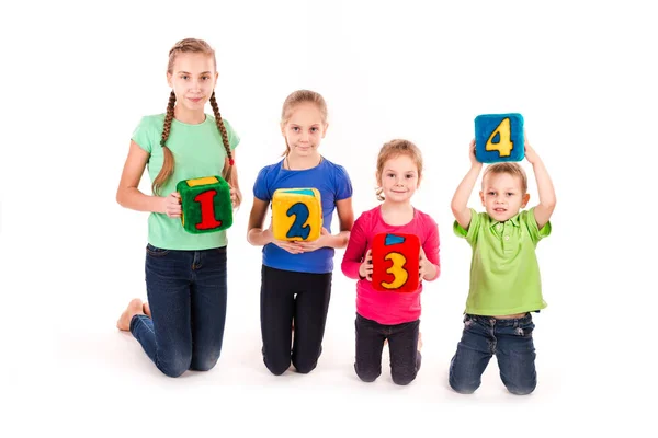 Happy kids holding blocks with numbers over white background — Stock Photo, Image