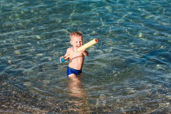 Miúdo feliz bonito brincando com pistola de água — Fotografia de Stock