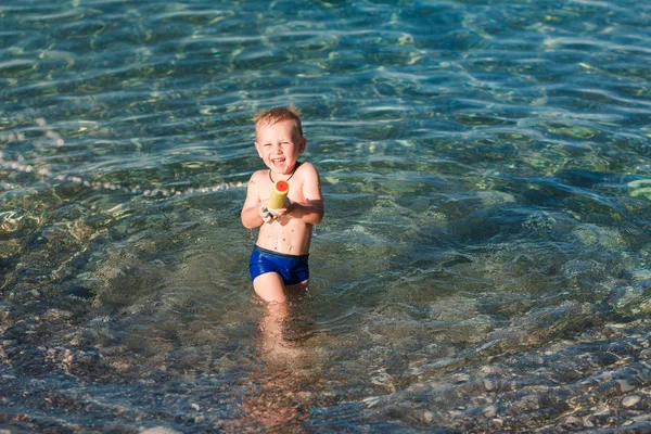 Lindo niño feliz jugando con pistola de agua — Foto de Stock