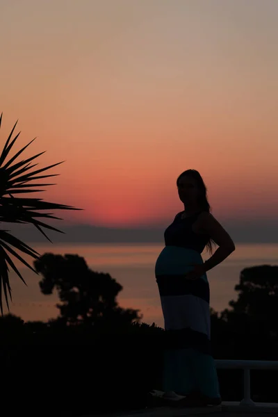 Silueta unei femei însărcinate pe plajă la apusul soarelui — Fotografie, imagine de stoc