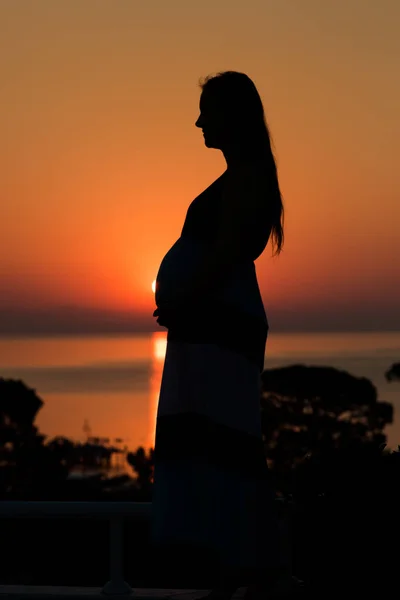 日落时一个孕妇在海滩上的侧影 — 图库照片