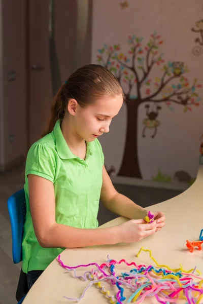 Cute little girl creating toys with chenille sticks — Stock Photo, Image