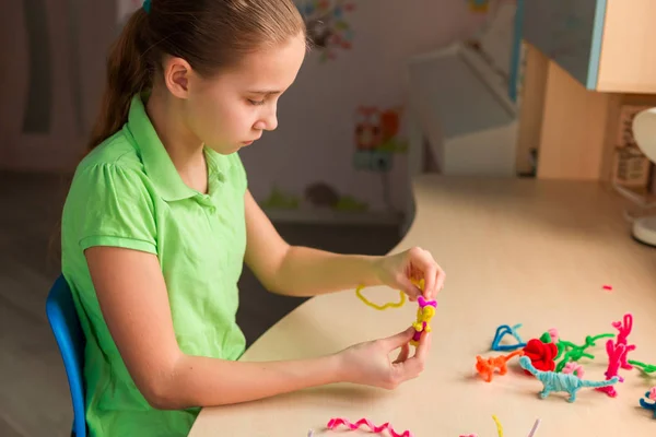 Linda niña creando juguetes con palos de chenilla —  Fotos de Stock