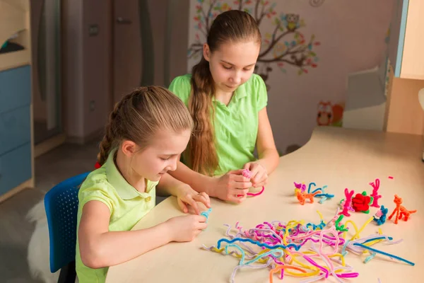 Cute little girls creating toys with chenille sticks — Stock Photo, Image