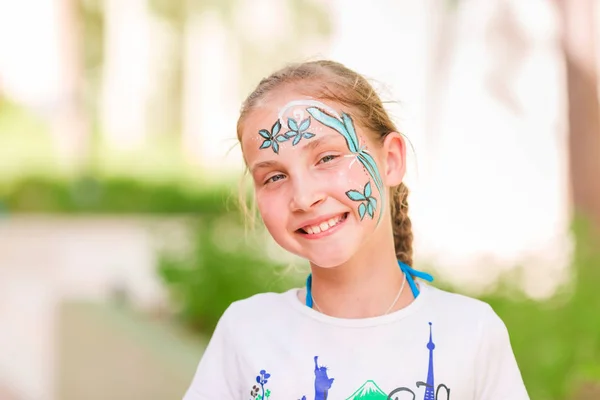 Szczęśliwa dziewczynka z farby sztuka twarz w parku. — Zdjęcie stockowe