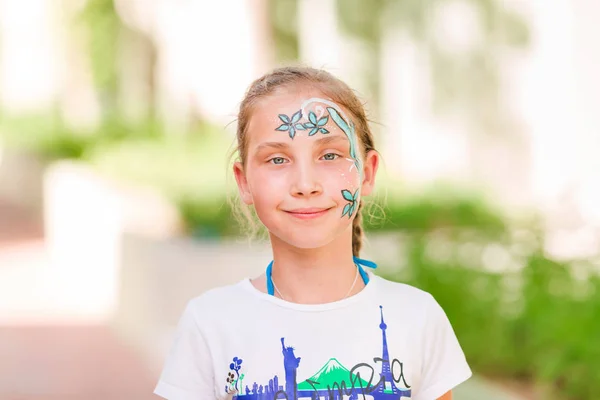 Boldog kislány arc art festék a parkban. — Stock Fotó