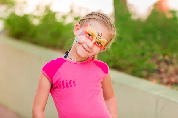 Szczęśliwa dziewczynka z farby sztuka twarz w parku. — Zdjęcie stockowe