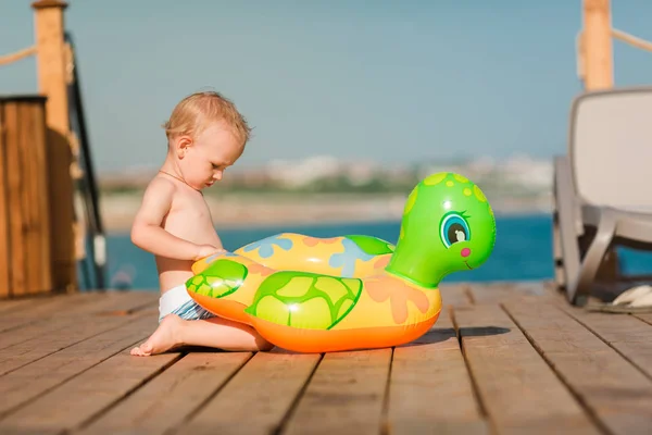 Lindo niño jugando con la boya de la vida en la playa — Foto de Stock