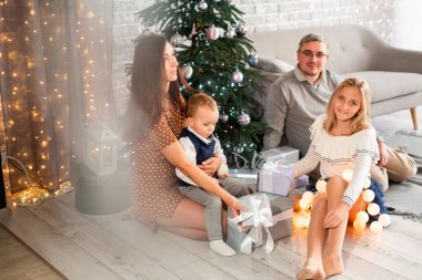 Mutlu aile Noel ağacının yanında eğleniyor.