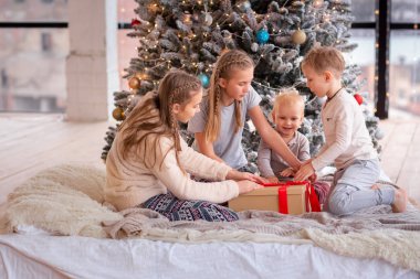 Mutlu çocuklar Noel ağacının yanında eğleniyor.