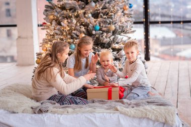 Mutlu çocuklar Noel ağacının yanında eğleniyor.