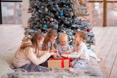 Mutlu çocuklar Noel ağacının yanında eğleniyor.