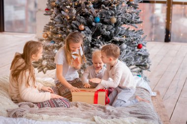 Mutlu çocuklar Noel ağacının yanında eğleniyor.